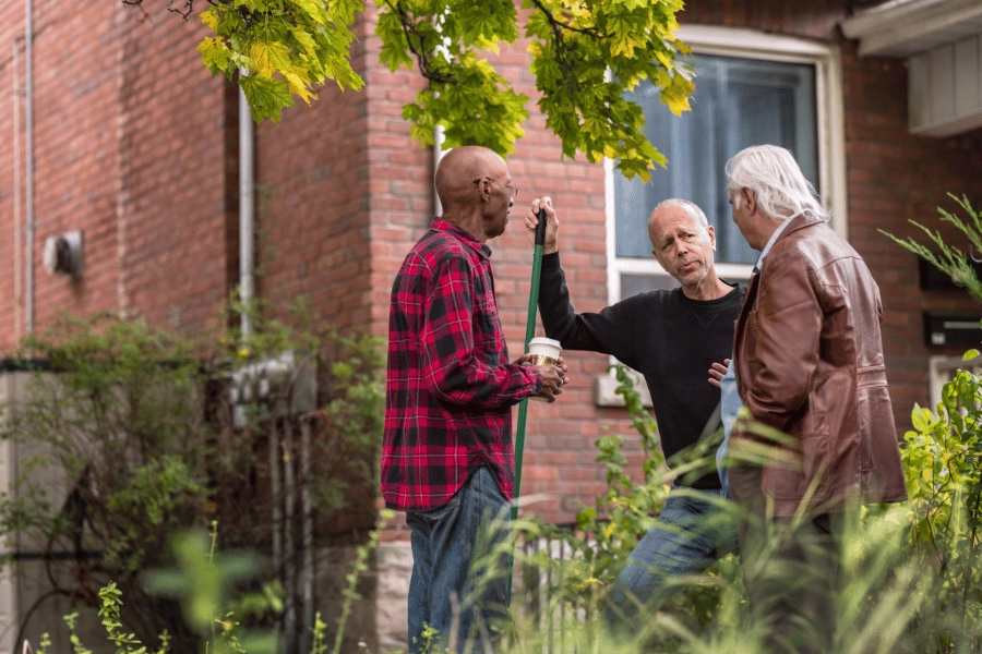 three neighbors hanging out in the front yard and talking 